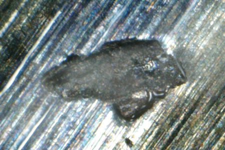 This magnified sample particle appears to be a metal chunk possibly caused by overloading and poor lubrication.